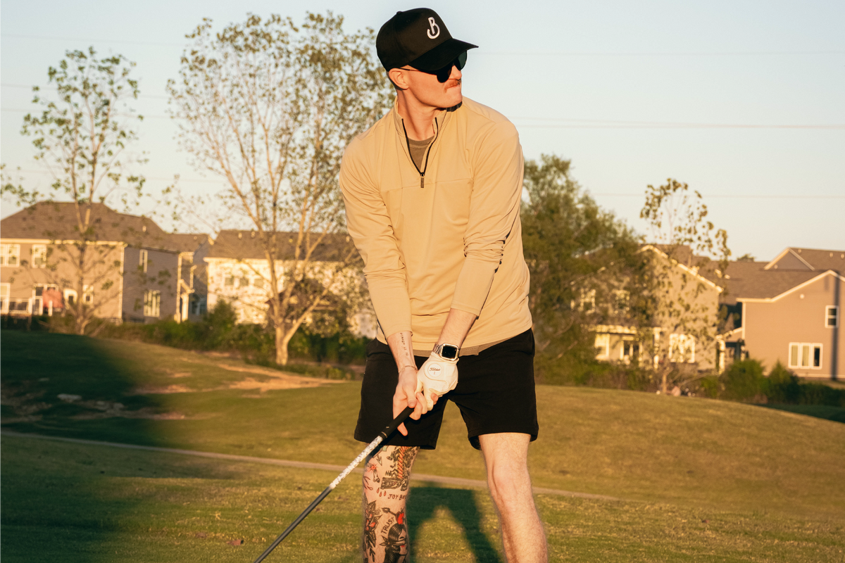 Person playing golf on a grassy field with houses in the background